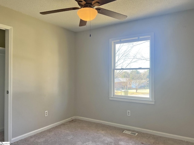 spare room with carpet floors, baseboards, visible vents, and a textured ceiling