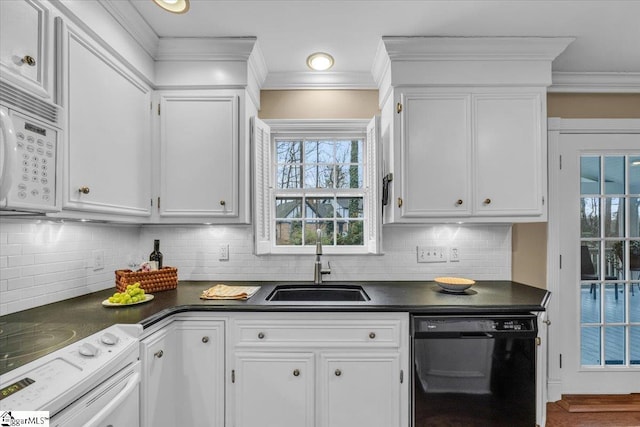 kitchen featuring dark countertops, white appliances, white cabinetry, and a sink