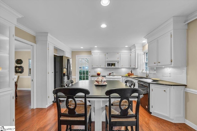 kitchen with black appliances, a sink, light wood-style flooring, and a healthy amount of sunlight