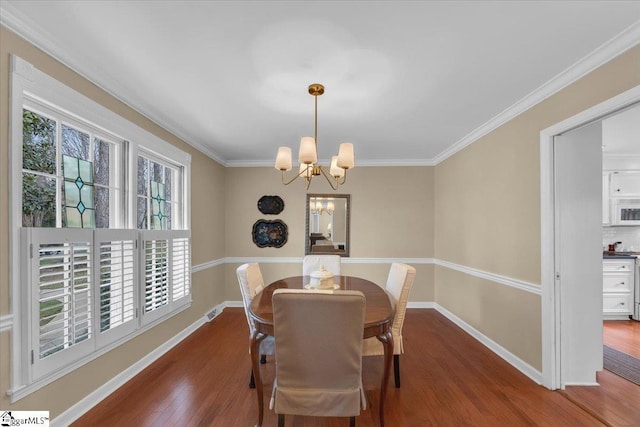 dining space with a chandelier, wood finished floors, visible vents, baseboards, and ornamental molding