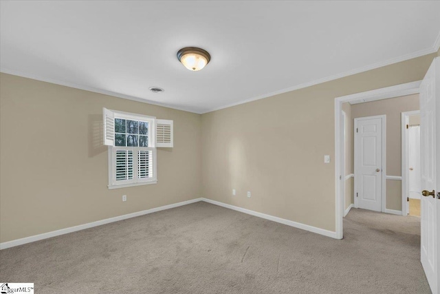 carpeted empty room with ornamental molding, visible vents, and baseboards