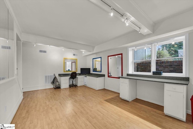 unfurnished office with visible vents, beamed ceiling, and built in desk