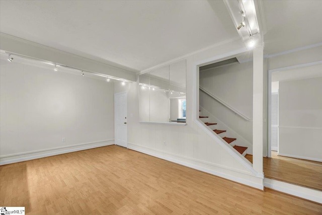 spare room with stairway, wood finished floors, and crown molding