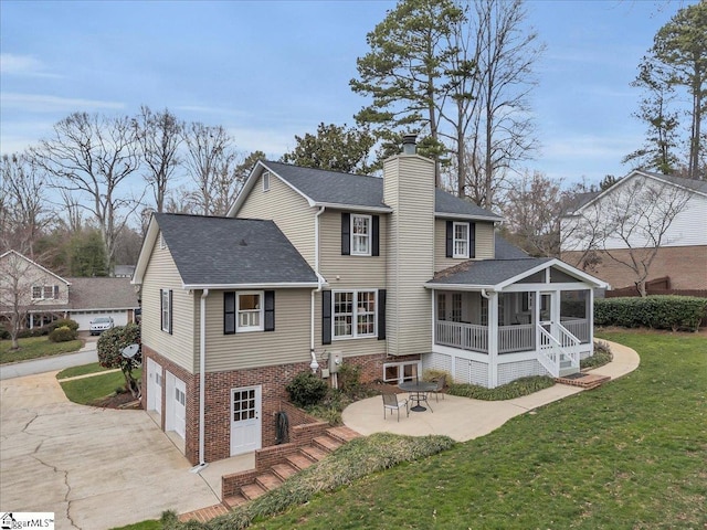 rear view of property featuring a patio, a sunroom, a chimney, an attached garage, and a yard