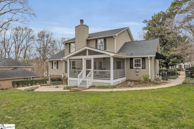 rear view of property with a patio, a chimney, a shingled roof, a lawn, and a sunroom