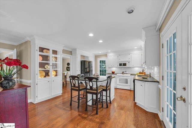 dining space with dark wood-type flooring, recessed lighting, and ornamental molding