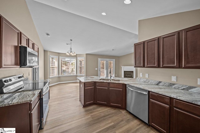 kitchen with a peninsula, vaulted ceiling, stainless steel appliances, and a sink