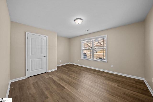 unfurnished room featuring wood finished floors, visible vents, and baseboards