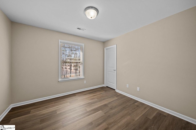 spare room featuring wood finished floors, visible vents, and baseboards