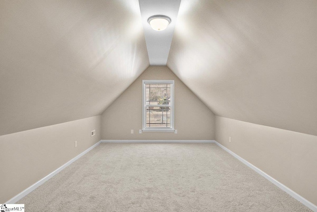 additional living space featuring light carpet, vaulted ceiling, and baseboards