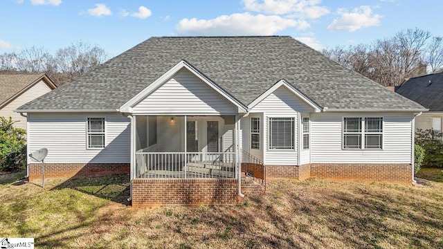 view of front of property featuring a sunroom, a front lawn, and roof with shingles