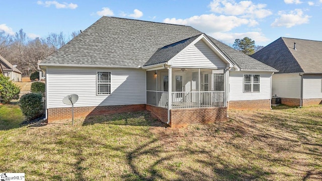 rear view of house featuring roof with shingles, a lawn, and a sunroom