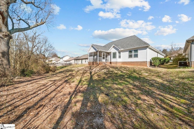 back of property featuring a sunroom, central AC, and a lawn