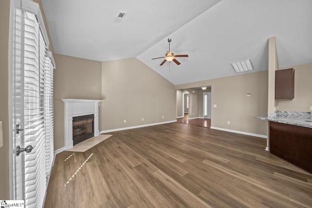 unfurnished living room with a fireplace with flush hearth, vaulted ceiling, ceiling fan, wood finished floors, and baseboards