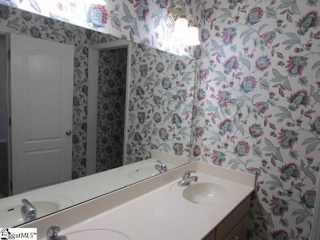 bathroom featuring double vanity, a sink, and wallpapered walls