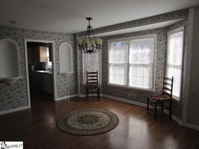 dining area featuring wood finished floors, plenty of natural light, an inviting chandelier, and wallpapered walls