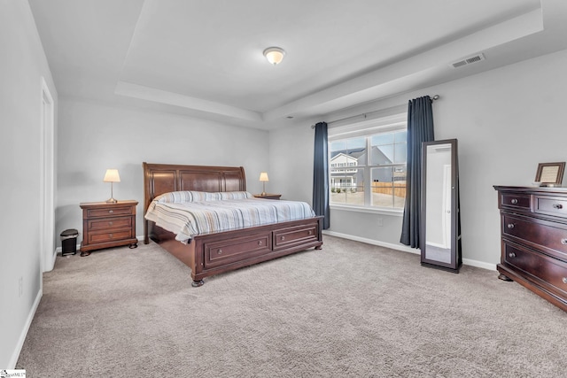 bedroom featuring carpet floors, a raised ceiling, visible vents, and baseboards