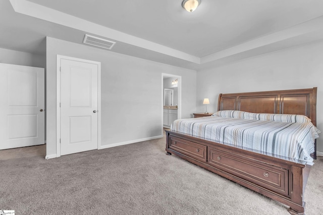 bedroom featuring carpet, a raised ceiling, visible vents, ensuite bathroom, and baseboards