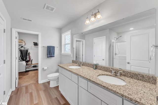 full bath with double vanity, wood finished floors, walk in shower, and a sink