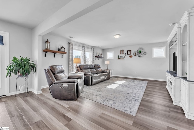 living room featuring visible vents, baseboards, and wood finished floors