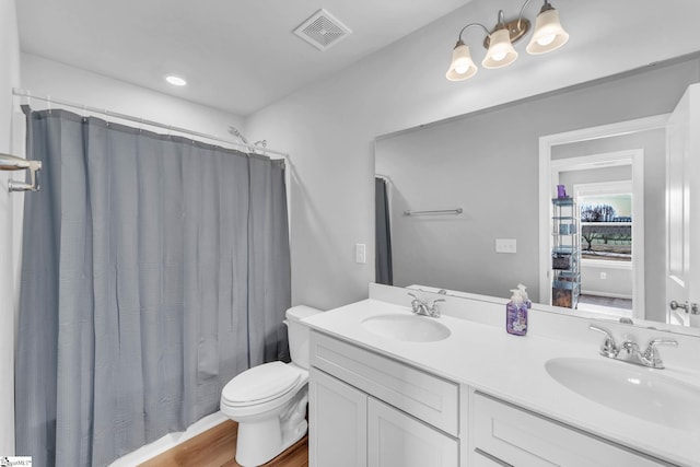 full bathroom with visible vents, a sink, toilet, and double vanity