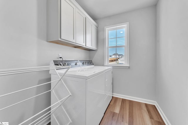 laundry room featuring washer and clothes dryer, light wood-type flooring, cabinet space, and baseboards