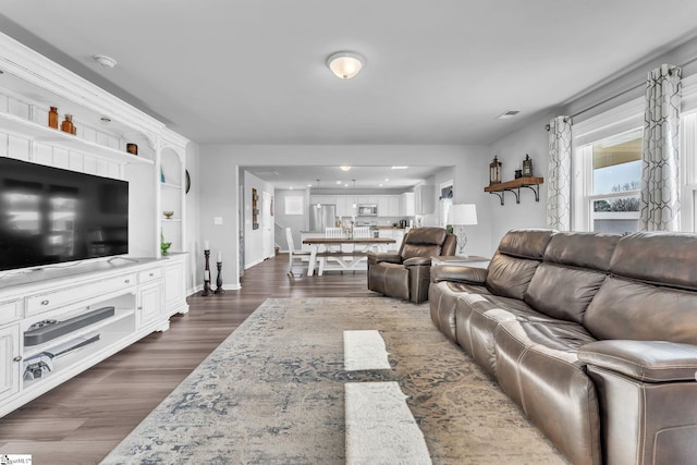 living area featuring dark wood-type flooring, visible vents, and baseboards