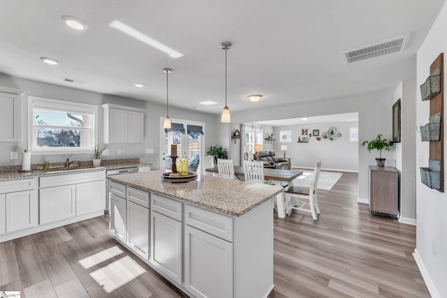 kitchen featuring a center island, visible vents, hanging light fixtures, and light wood finished floors