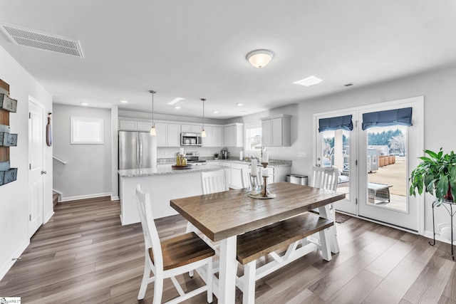 dining area with dark wood-type flooring, plenty of natural light, and visible vents