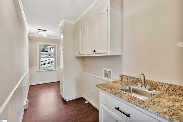 kitchen featuring a sink, white cabinets, wainscoting, dark wood-style floors, and crown molding