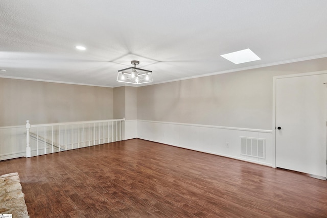 unfurnished room featuring ornamental molding, a skylight, visible vents, and wood finished floors