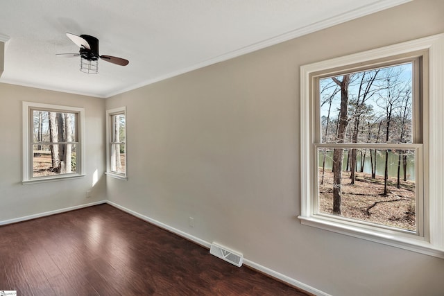 empty room with baseboards, crown molding, visible vents, and dark wood-style flooring