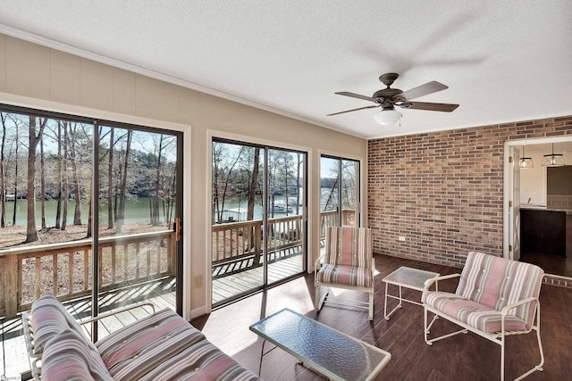 sunroom / solarium featuring a water view and a ceiling fan