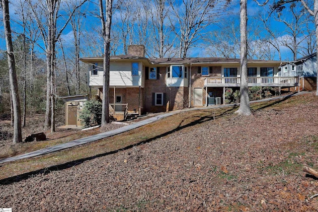 back of house featuring a chimney, an outbuilding, and brick siding