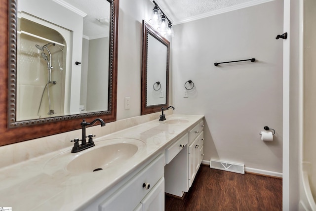 full bathroom featuring visible vents, ornamental molding, a sink, and wood finished floors