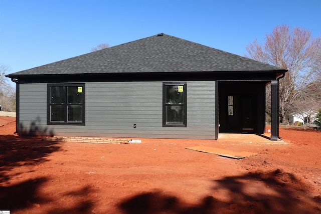 rear view of property with roof with shingles and a patio area