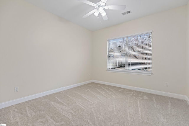 empty room featuring light colored carpet, visible vents, ceiling fan, and baseboards