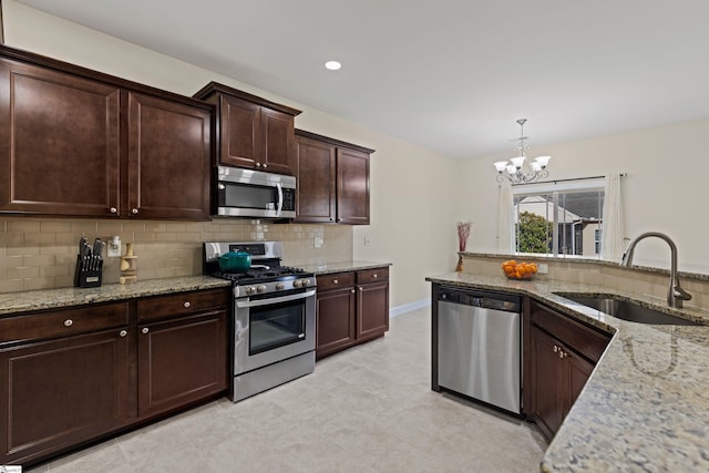 kitchen featuring light stone countertops, backsplash, stainless steel appliances, and a sink