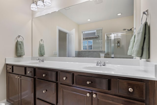 bathroom featuring a stall shower, a sink, and double vanity