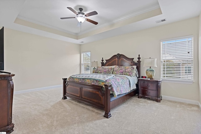 carpeted bedroom with ornamental molding, a tray ceiling, visible vents, and baseboards