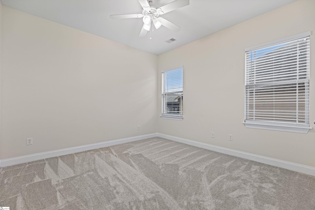 unfurnished room with a ceiling fan, visible vents, light carpet, and baseboards