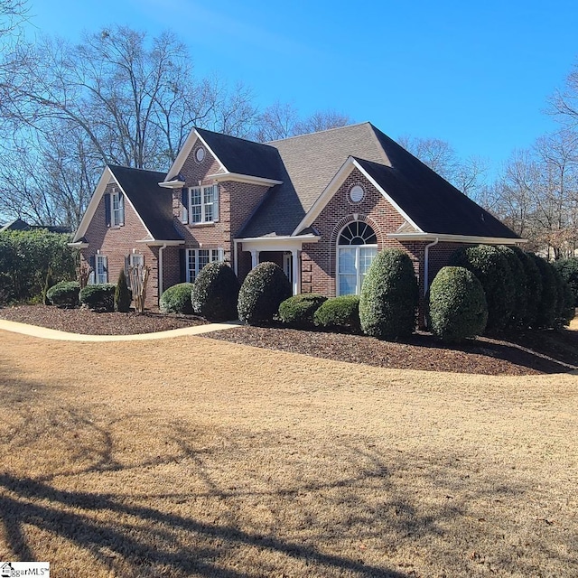 view of front of house with brick siding and a front lawn