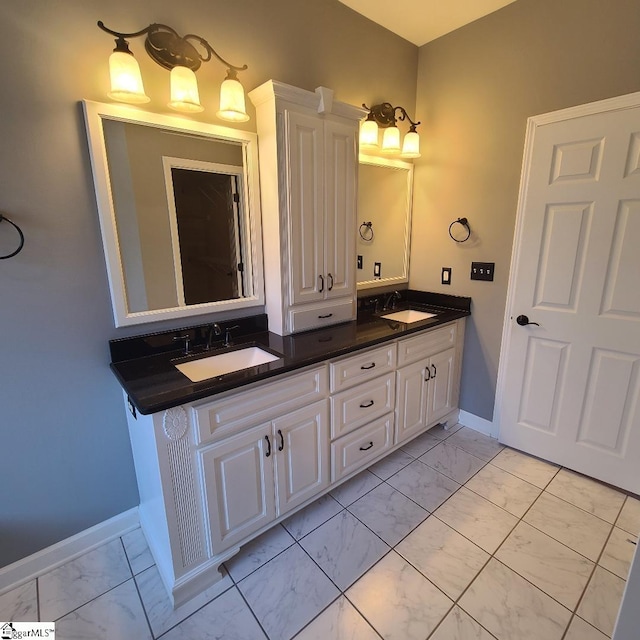 full bath with marble finish floor, a sink, baseboards, and double vanity