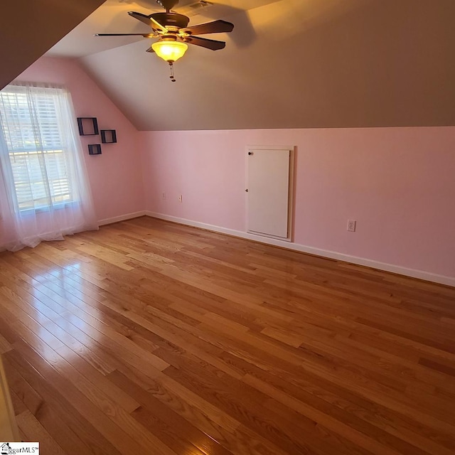 additional living space with lofted ceiling, ceiling fan, light wood-style flooring, and baseboards