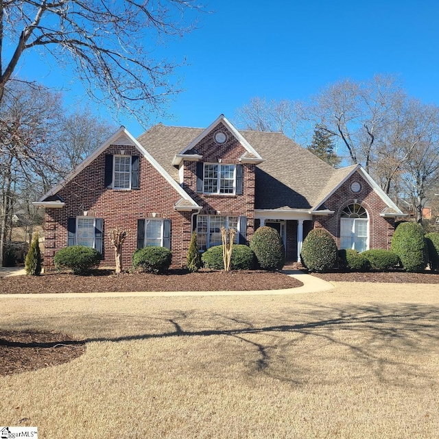 view of front of house featuring brick siding and roof with shingles