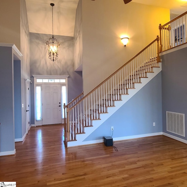 foyer with baseboards, a high ceiling, visible vents, and wood finished floors