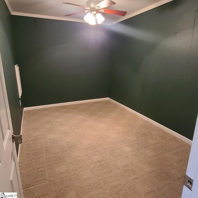 carpeted spare room featuring baseboards, ornamental molding, and a ceiling fan