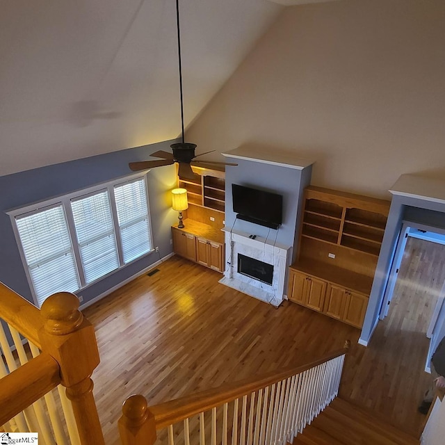 living room featuring ceiling fan, high vaulted ceiling, wood finished floors, visible vents, and a high end fireplace