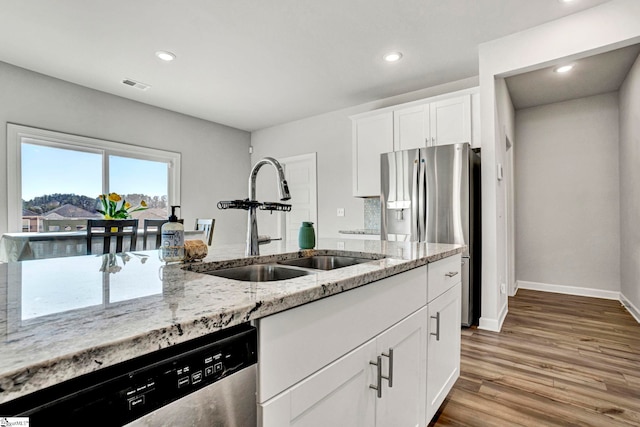 kitchen featuring light wood-style flooring, a sink, baseboards, appliances with stainless steel finishes, and light stone countertops