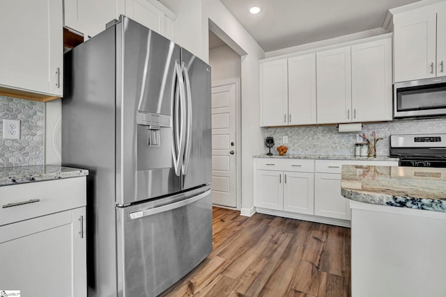 kitchen with stainless steel appliances, white cabinets, light stone counters, and wood finished floors